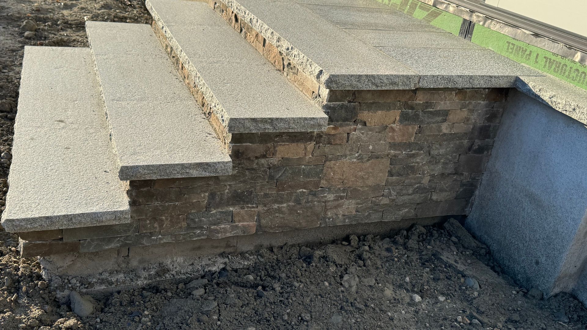 Stone wall with granite steps during construction on rocky ground