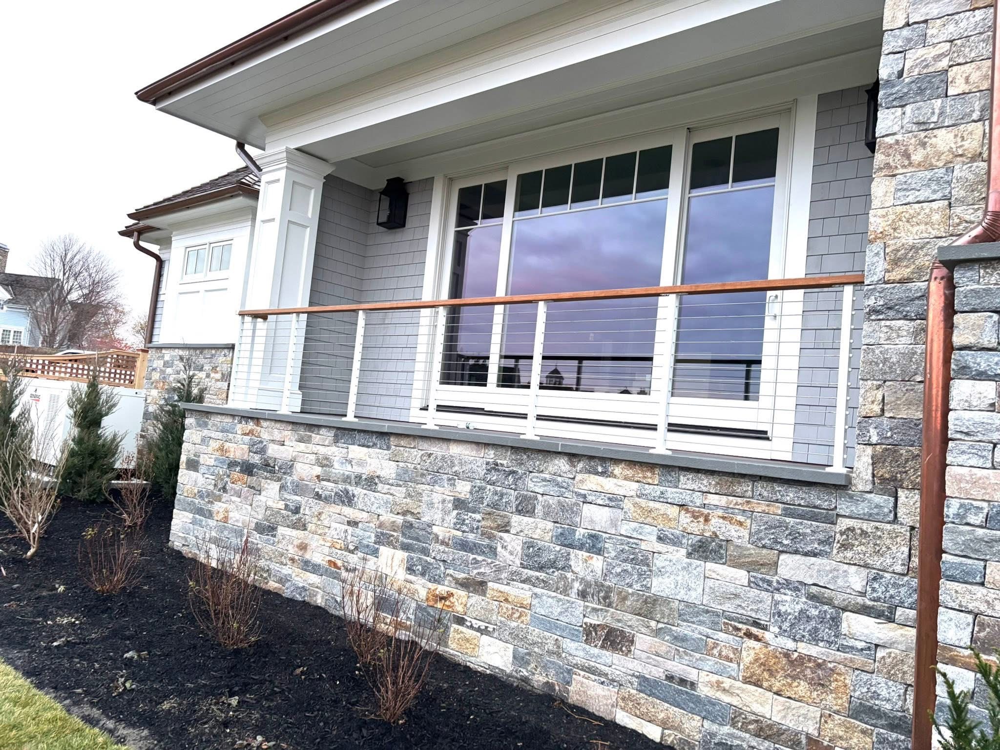 Modern house exterior with stone facade and white siding and railing